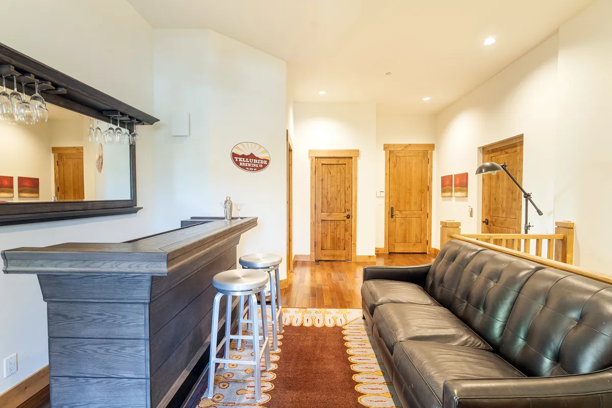 This image highlights a dedicated bar and lounge area, complete with a comfortable sofa, decorative rug, and wooden doors, creating a welcoming ambiance for socializing and entertaining guests.