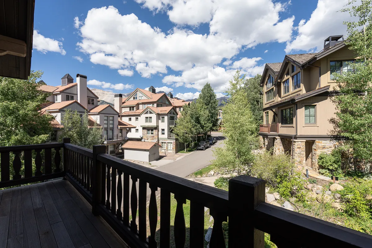 A serene view from the private balcony, with a railing overlooking nearby buildings, treetops, and a cloudy sky. The balcony promises moments of peace and mountain air just steps from the heart of the home.